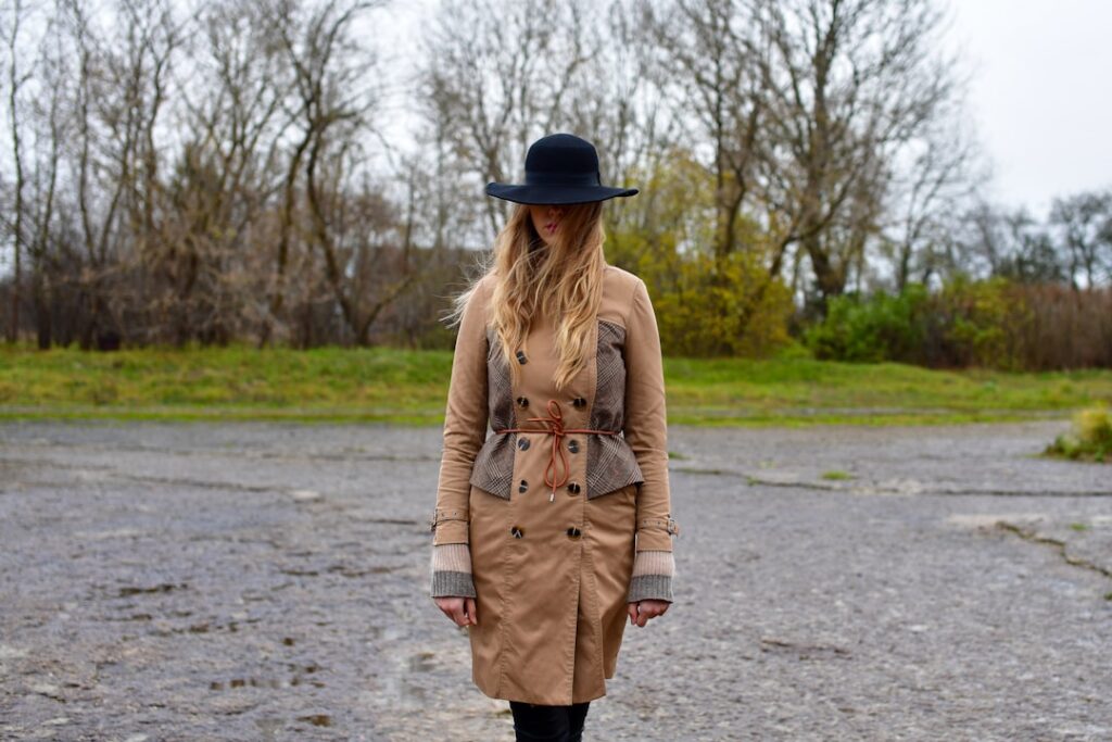 Woman in hat and coat standing outdoors