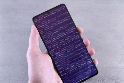 Hand holding smartphone displaying lines of code