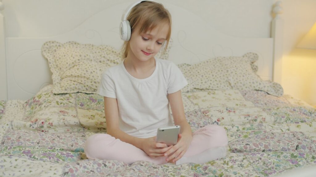 A young girl listens to music on her phone.