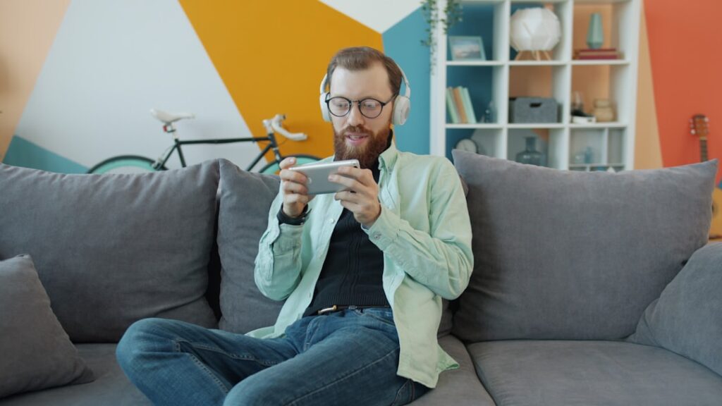 Man with headphones playing on phone on his phone