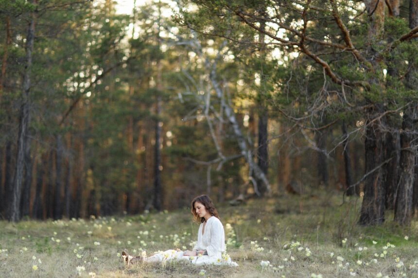 a woman sitting in the middle of a forest