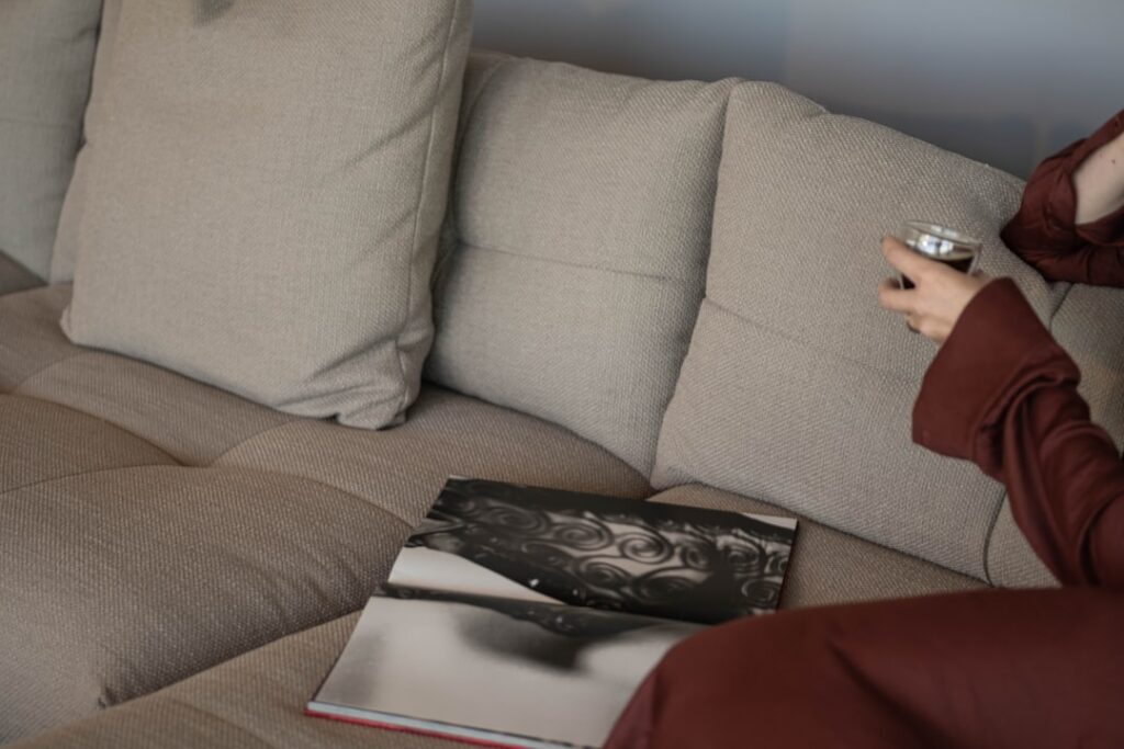 Person relaxing on a sofa with a drink and book