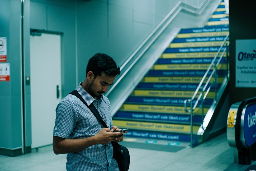 man in blue and white stripe polo shirt using smartphone