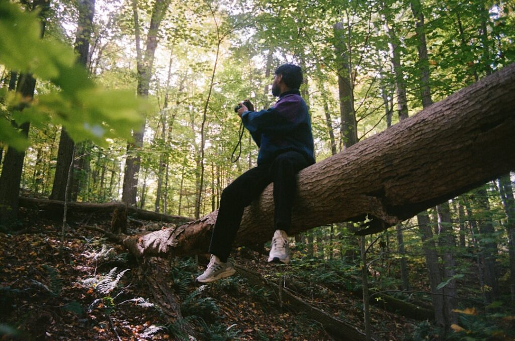 Man sitting on a fallen tree in the forest