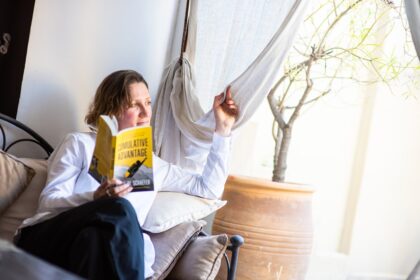 woman in white long sleeve shirt sitting on chair reading book