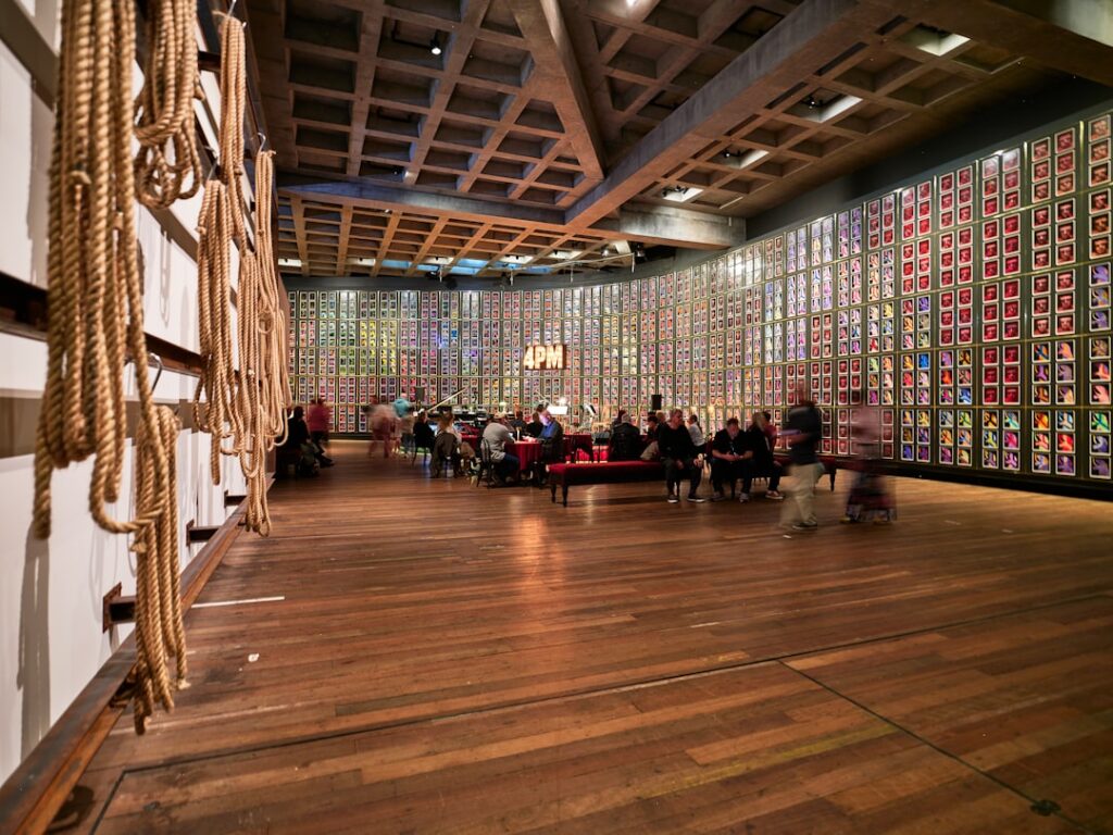People gathered in a brightly lit room with patterned walls.