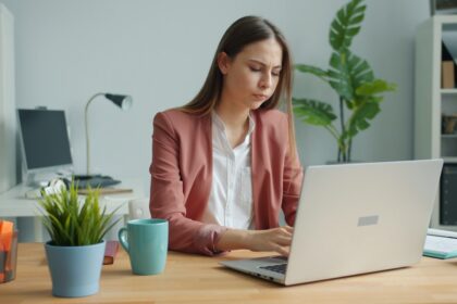 Young woman working on a laptop at a desk.
