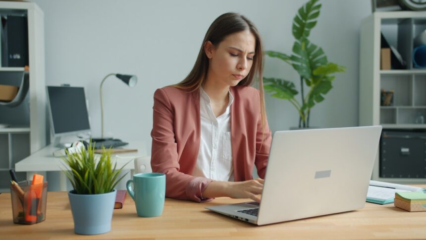 Young woman working on a laptop at a desk.