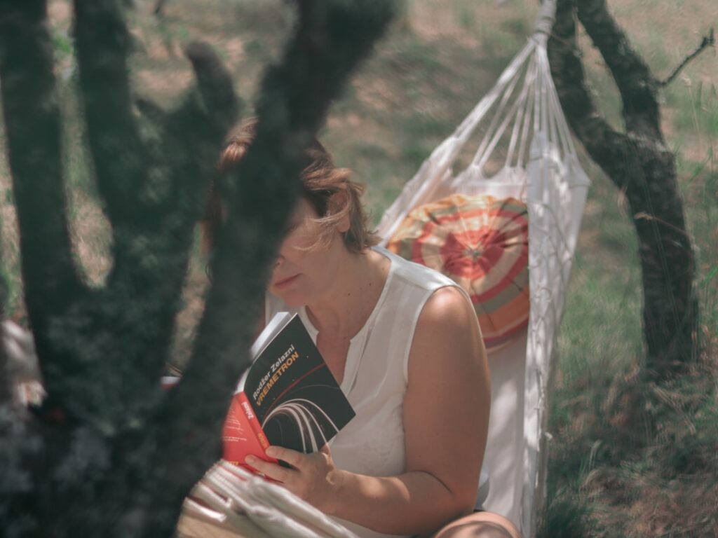 A woman sitting in a hammock reading a book