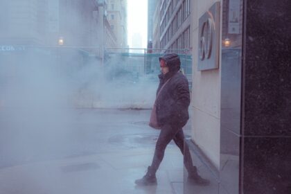 Person walking through steam on a city street.