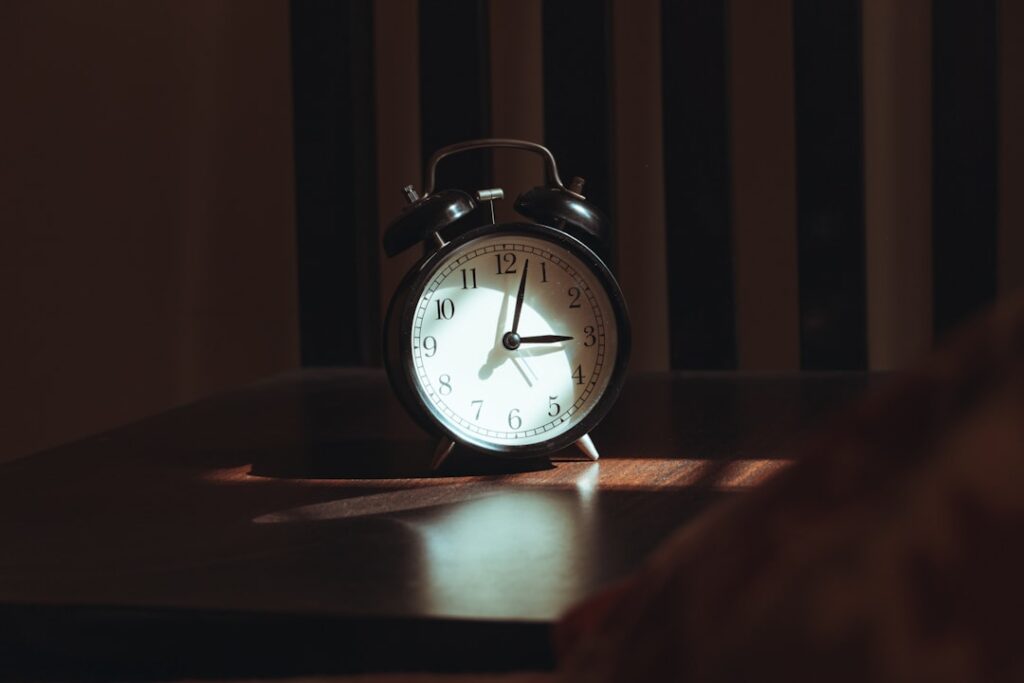 An alarm clock on a wooden table at night