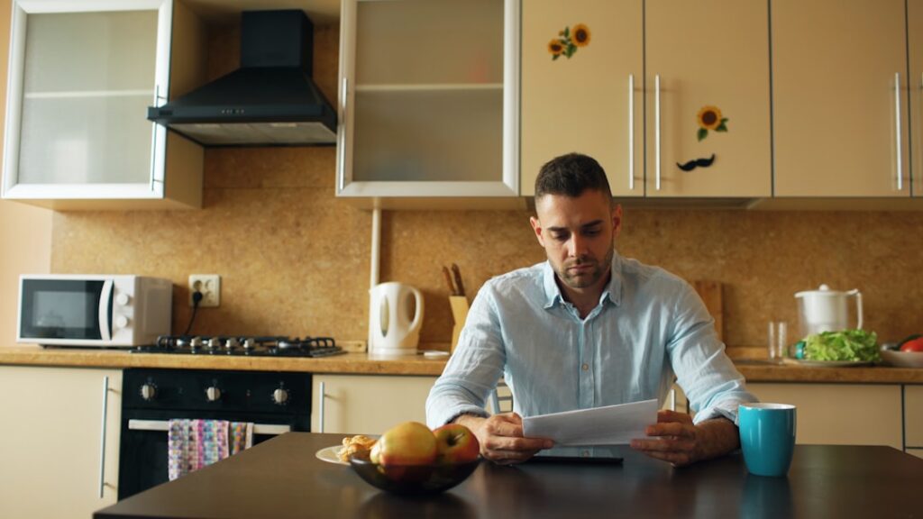 Man reading document at kitchen table with coffee