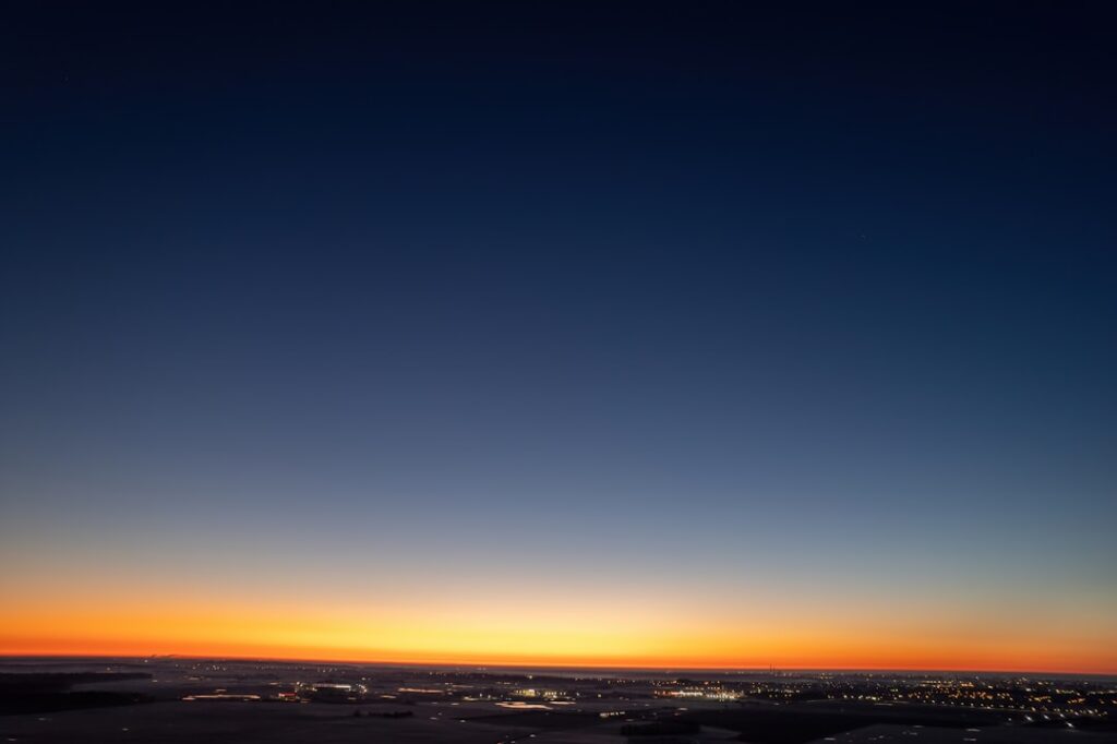 the sun is setting over the city lights