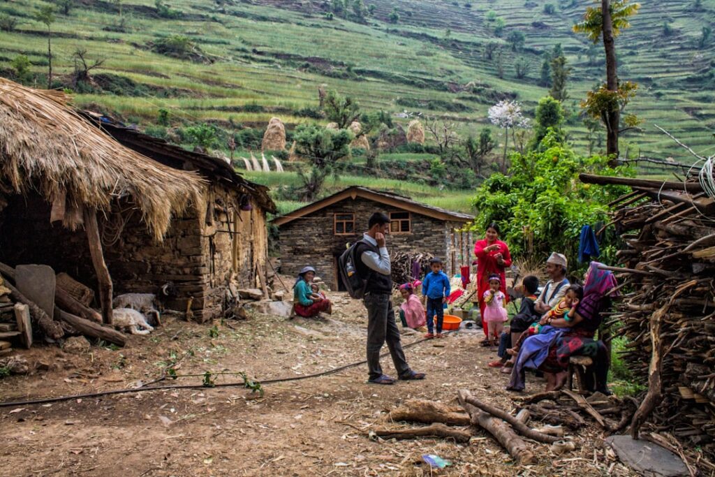 People gathered outside rural homes in a hilly village.