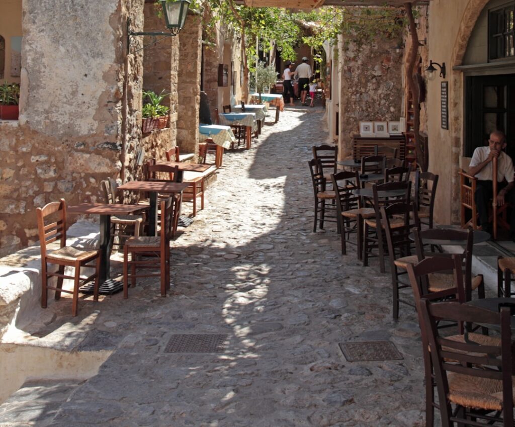 Outdoor cafe tables line a cobblestone street.