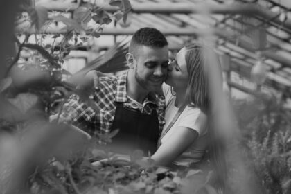 Couple sharing a tender moment in a greenhouse.