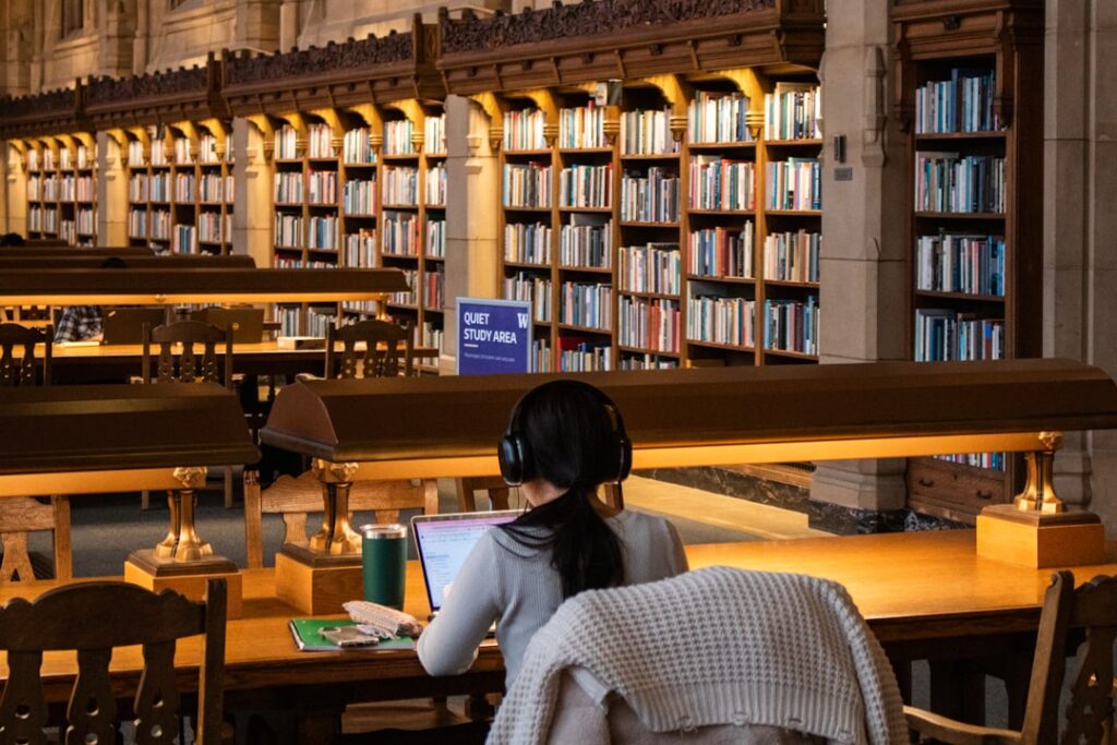 Student studies at a library with books.