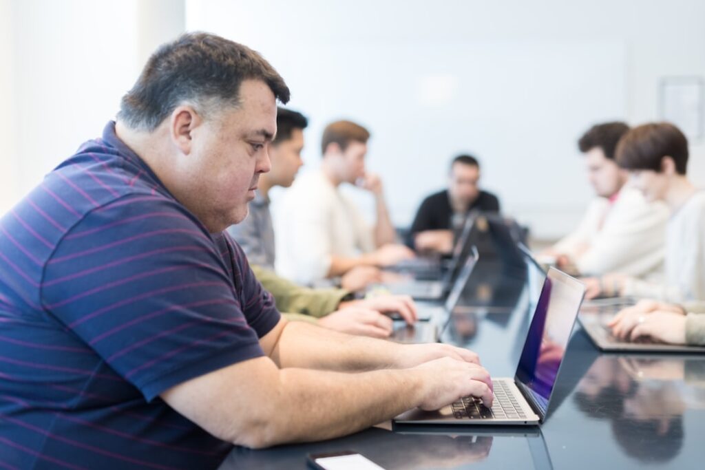a group of people sitting at a table with laptops
