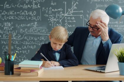 Teacher helping young student with math problems at desk.