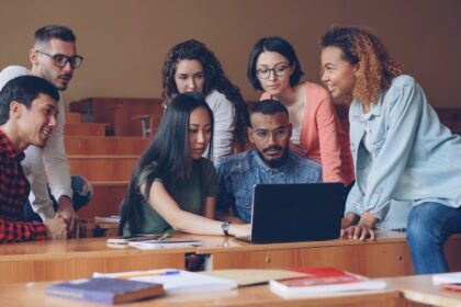 Diverse group of students gathered around a laptop.