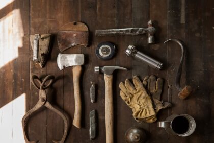 clothes iron, hammer, axe, flashlight and pitcher on brown wooden table