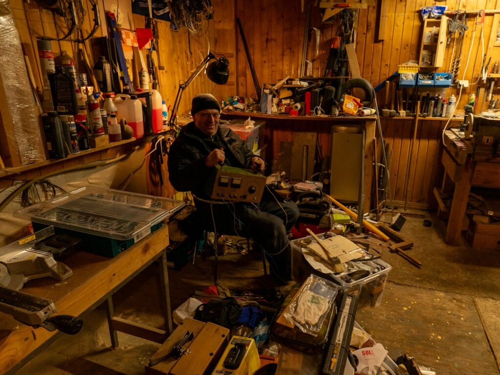 a man sitting in a workshop working on a laptop