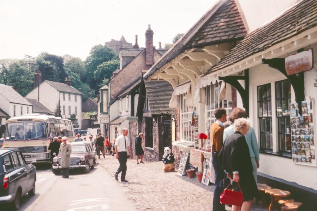 People walking on a street with shops and a bus.