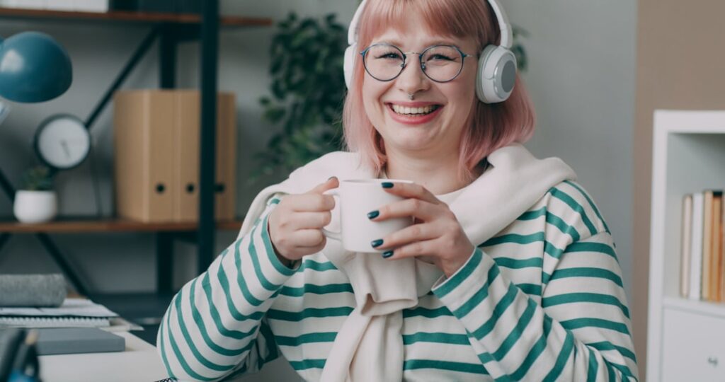 A woman wearing headphones and holding a cup