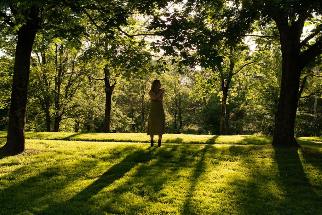 A woman standing in the shade of some trees