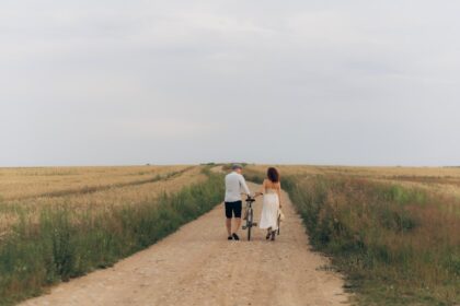 Couple walking with a bicycle on a dirt road