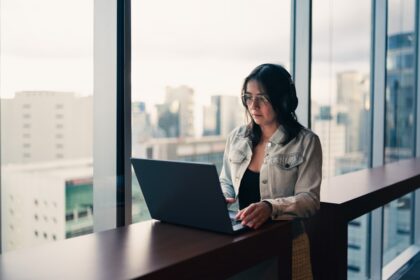 Woman wearing headphones working on a laptop by window
