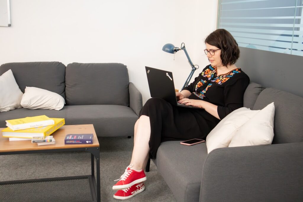 a woman sitting on a couch using a laptop computer