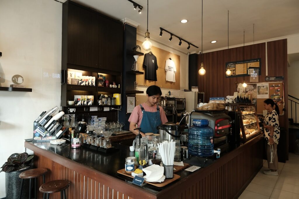 Barista preparing drinks behind a coffee shop counter.