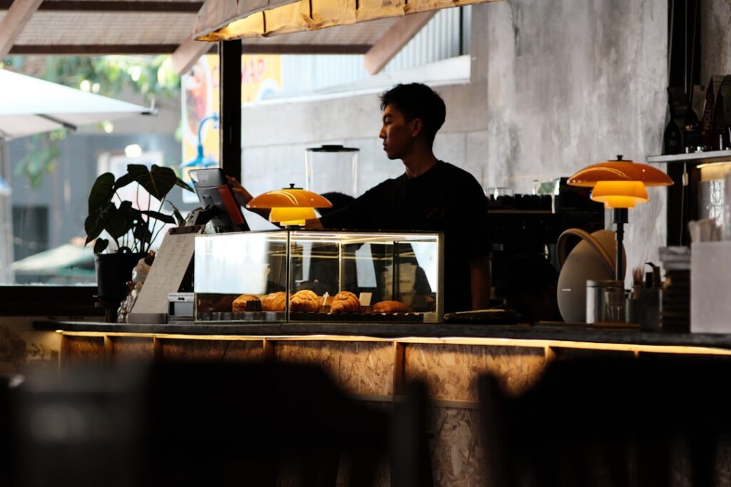 Barista preparing coffee behind a counter with pastries.