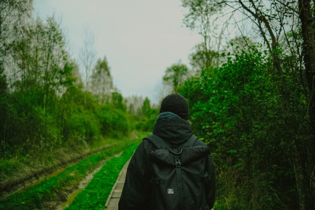 Person with backpack walking on a path through trees