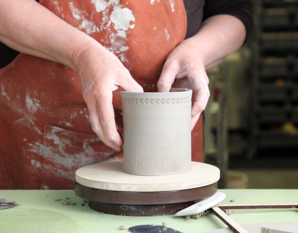 Hands shaping clay on a pottery wheel