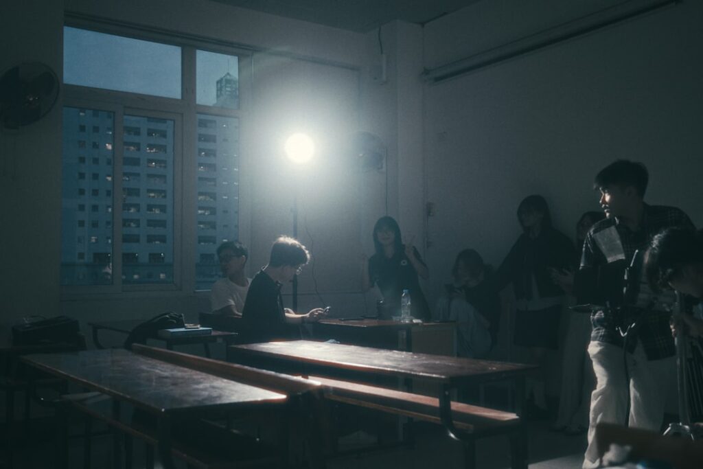 A group of people sit in a dimly lit classroom.