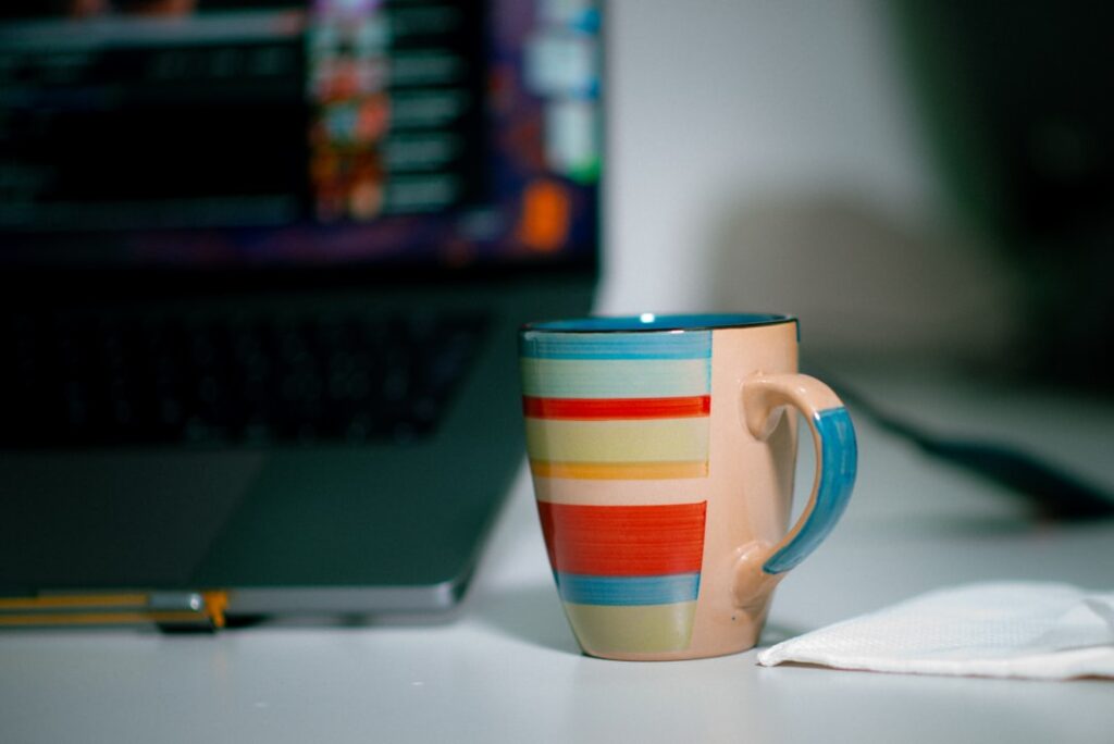 a coffee cup sitting next to a laptop computer