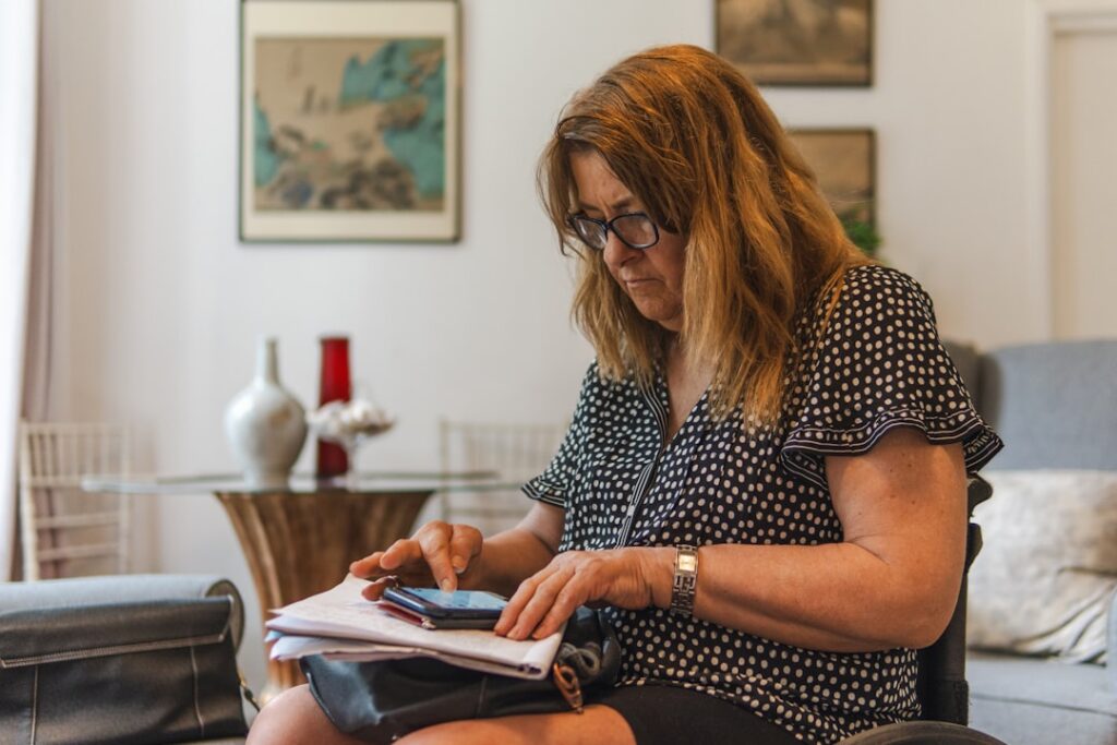 Woman looking at phone while writing on paper