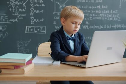 Boy in suit using laptop in classroom