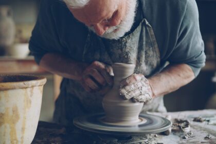 A potter shapes a clay vase on a spinning wheel.