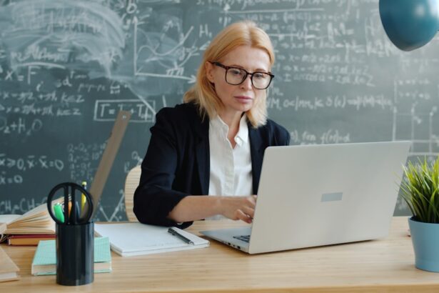 Woman working on a laptop in front of a chalkboard.