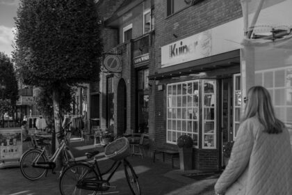 Woman walking past shops with parked bicycles