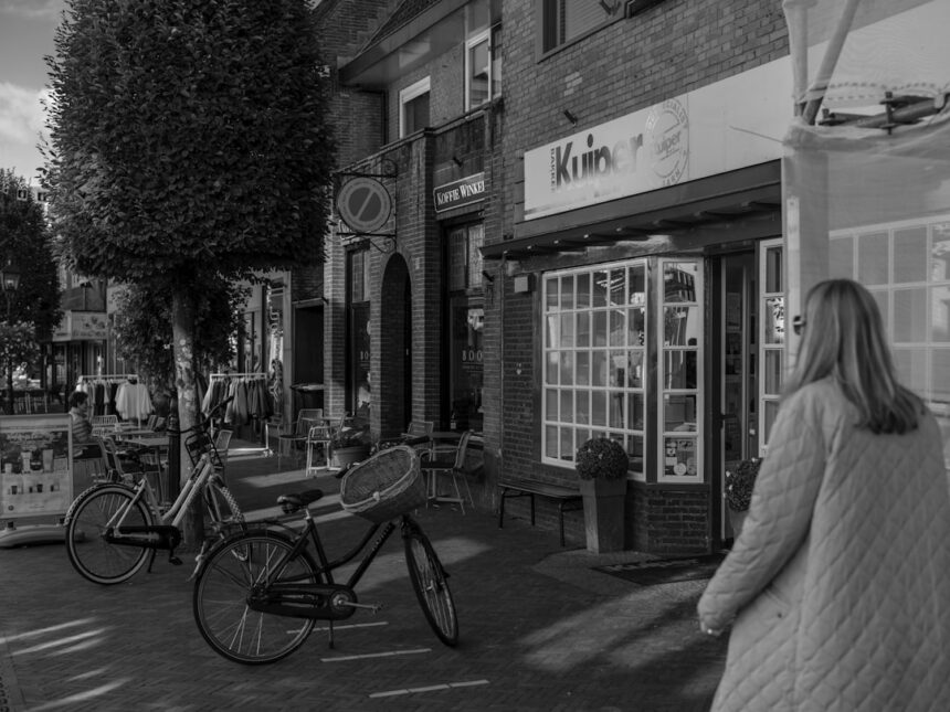 Woman walking past shops with parked bicycles
