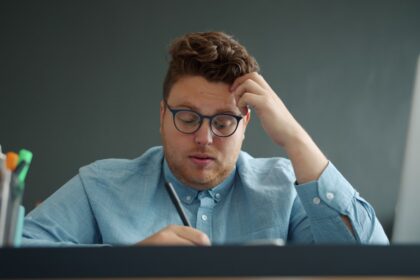 Man with glasses looking stressed at desk