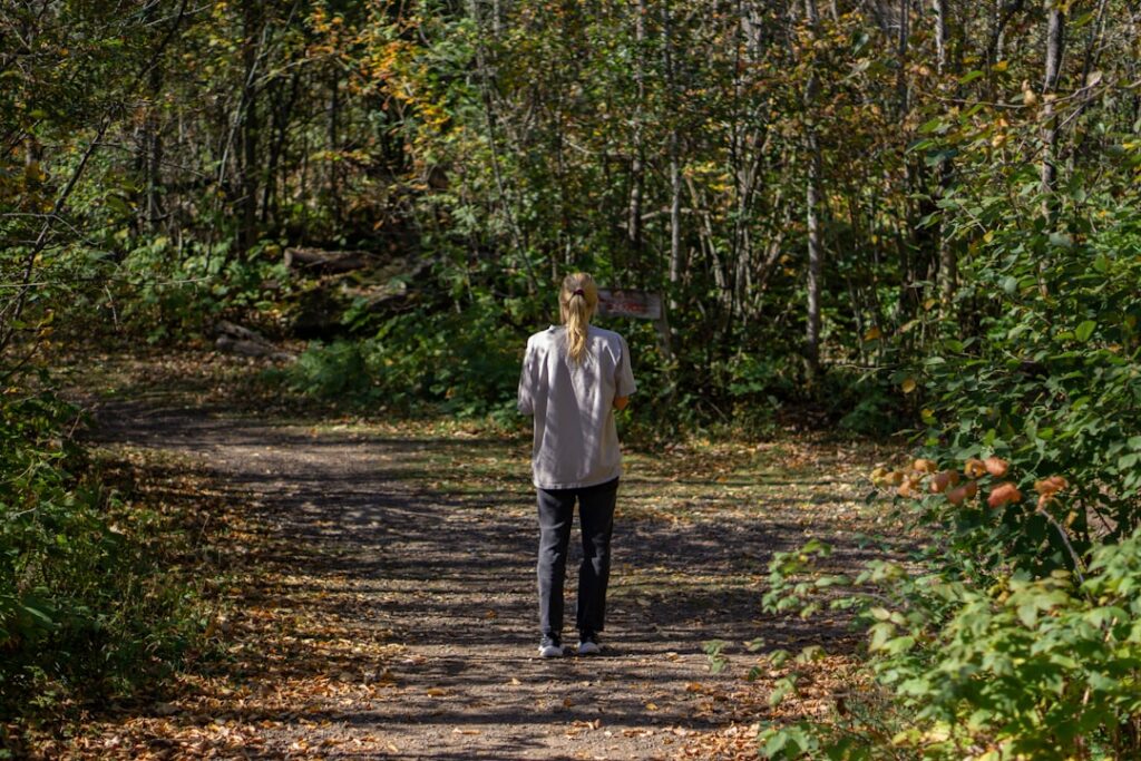 Woman walking on a path through an autumn forest.