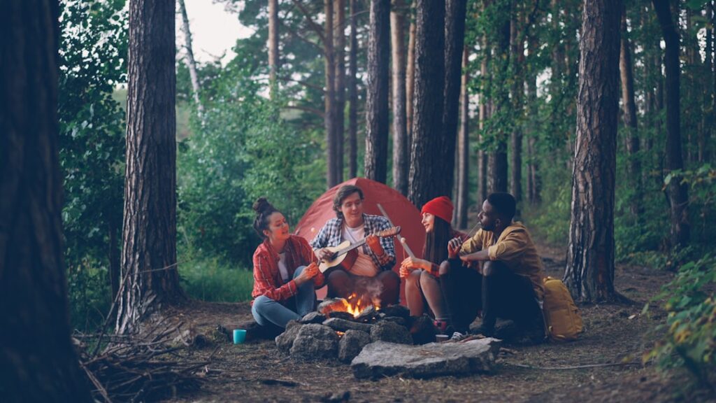Friends gathered around campfire at campsite in forest