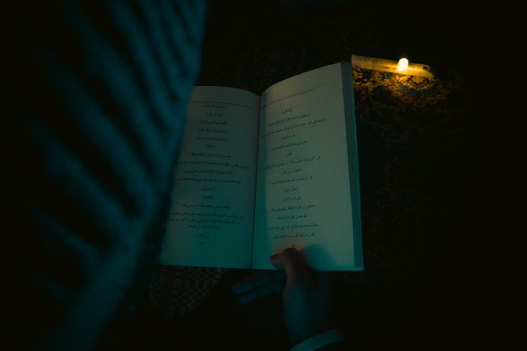 Person reading an open book by candlelight
