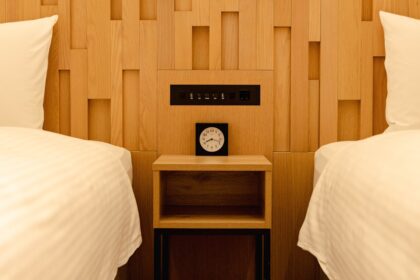 Two beds with a nightstand and clock between them.