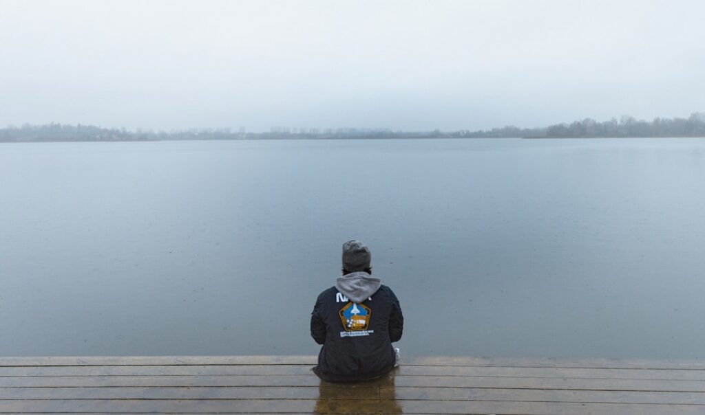A person sitting on a dock looking out at the water